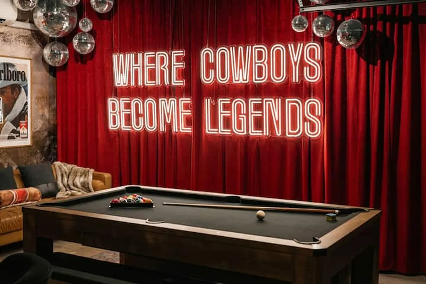 Pool table beneath the Where Cowboys Become Legends neon sign